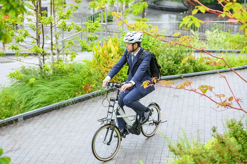 電動アシスト自転車のレンタルサービスを利用し、颯爽と営業の外回りをする男性