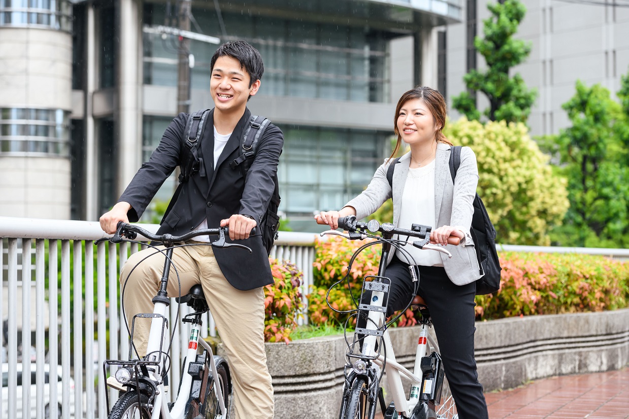 電動アシスト自転車のレンタルサービスを利用して営業の外回りをする上司と部下